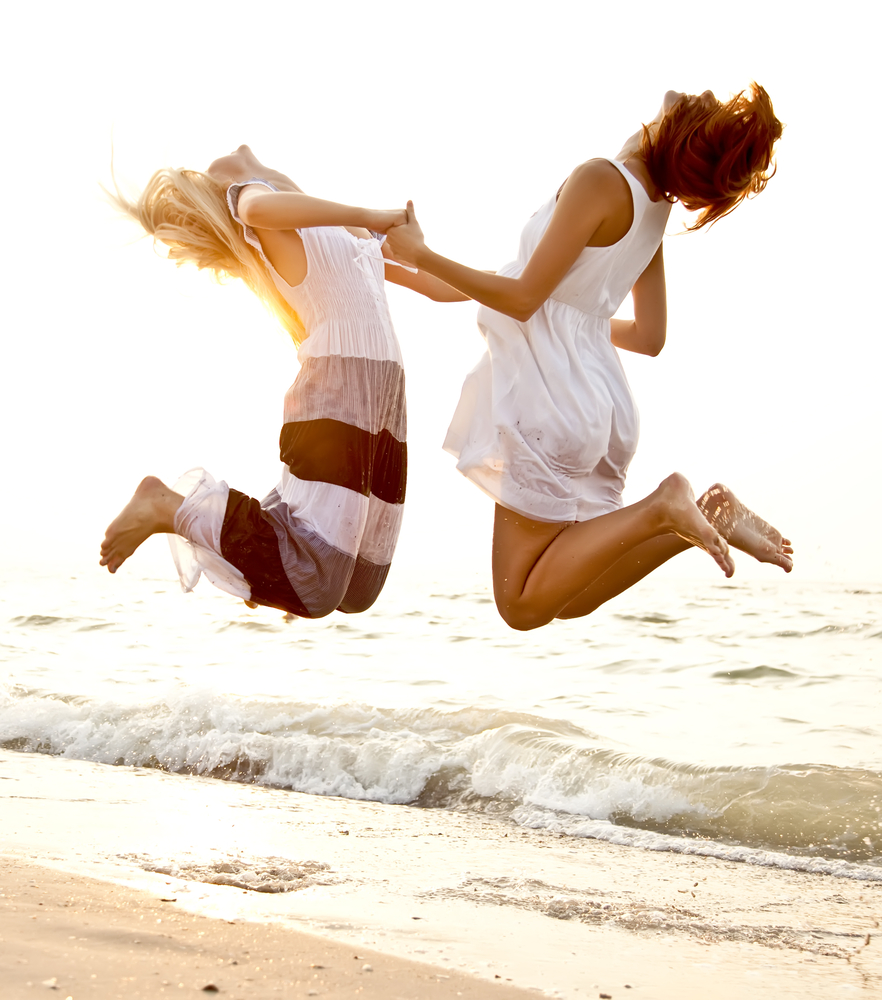 Я толще подруги. Прыжок на пляже. Молодая женщина с подругами сидит на пляже стоково. Happiness just for you.